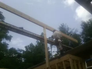 Carpenter setting a ridge beam over a new addition frame — Ice Dam Removal by Roofing Brothers in Valencia