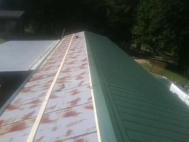 Old rusted panels beside newly installed green metal roofing — Wind Damage Roof Repair by Roofing Brothers in Valencia