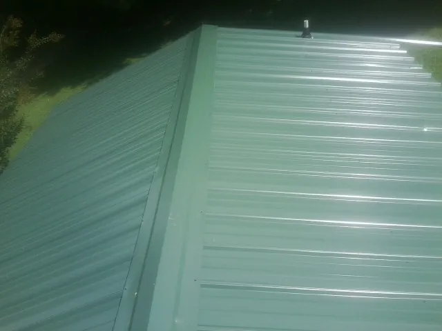 New green metal panels meeting at the ridge of a roof — Flat Roof Repair work by our crew in Valencia