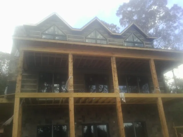 Dormers and porch framing on a large log home under construction — Roof Coating work by our crew in Valencia