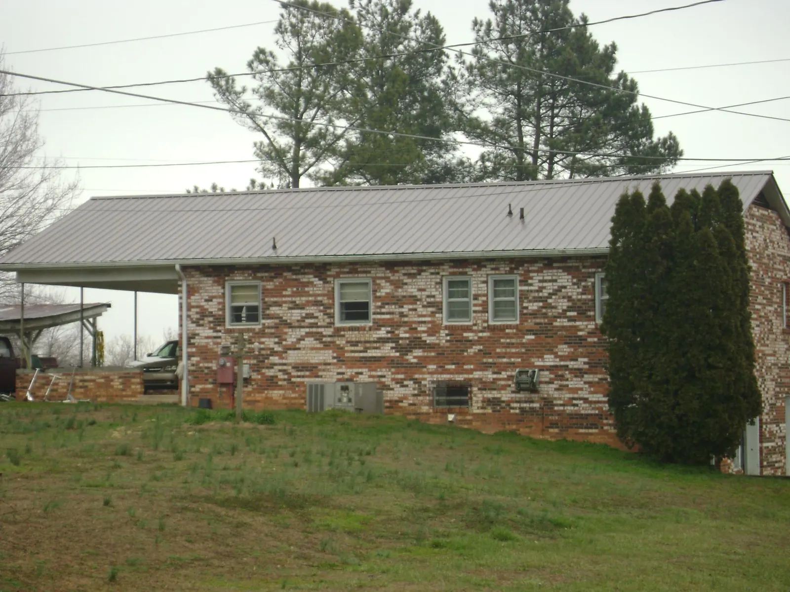 Gray metal roof on a brick split level home with a carport in Valencia