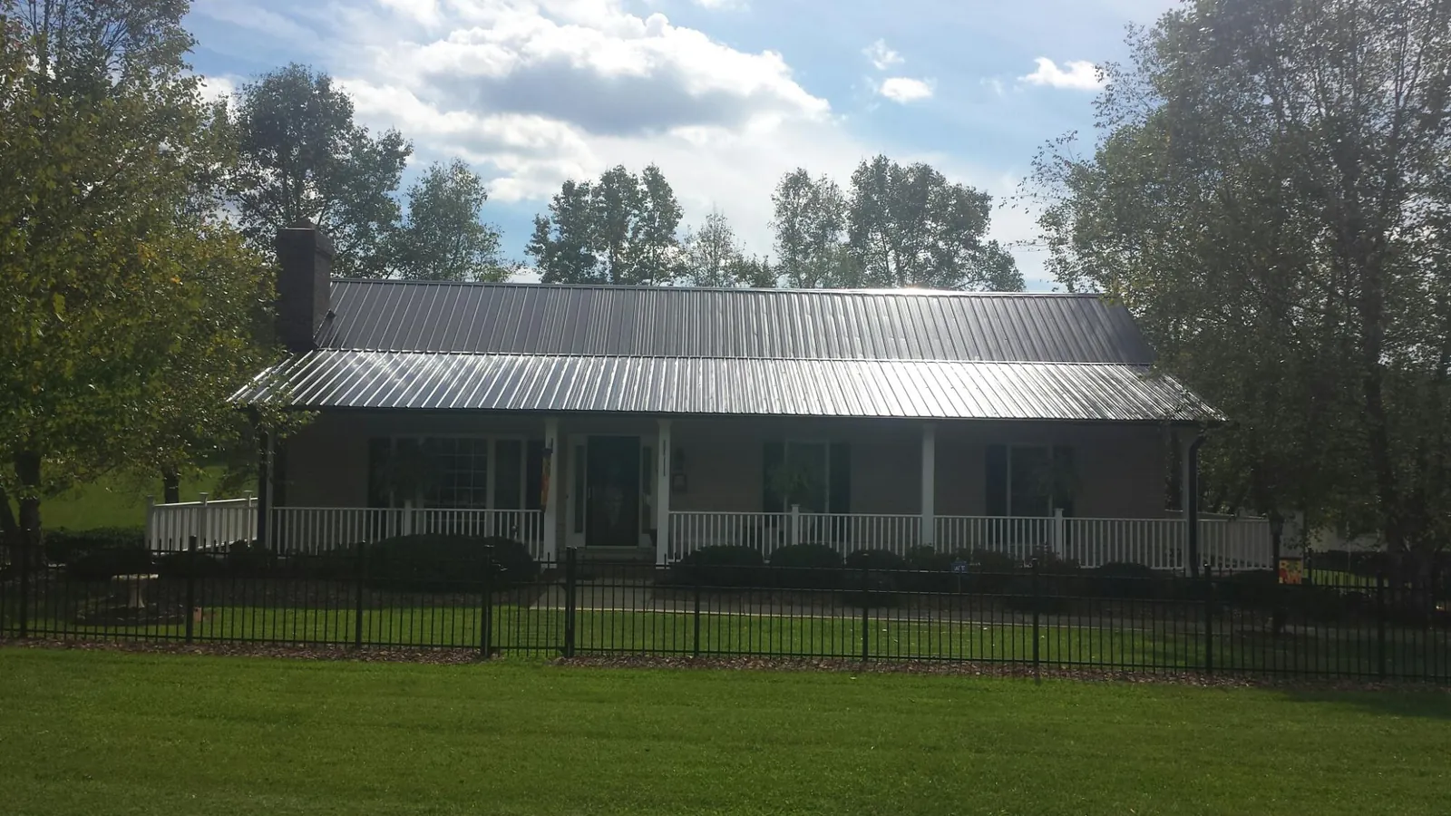 Gray metal roof on a brick ranch with a full width front porch — Gutter Guard Installation work by our crew in Valencia