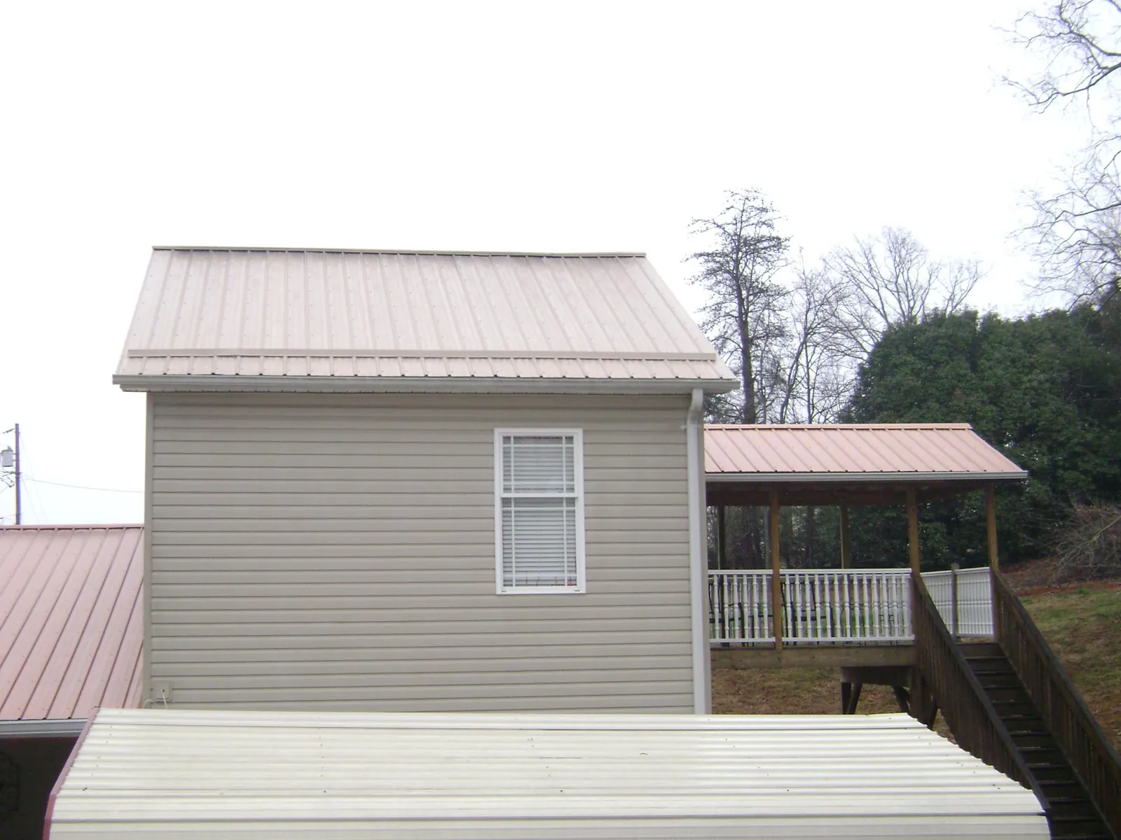 Tan metal roofs on a two story addition and attached porch, from a Roof Replacement job in Valencia
