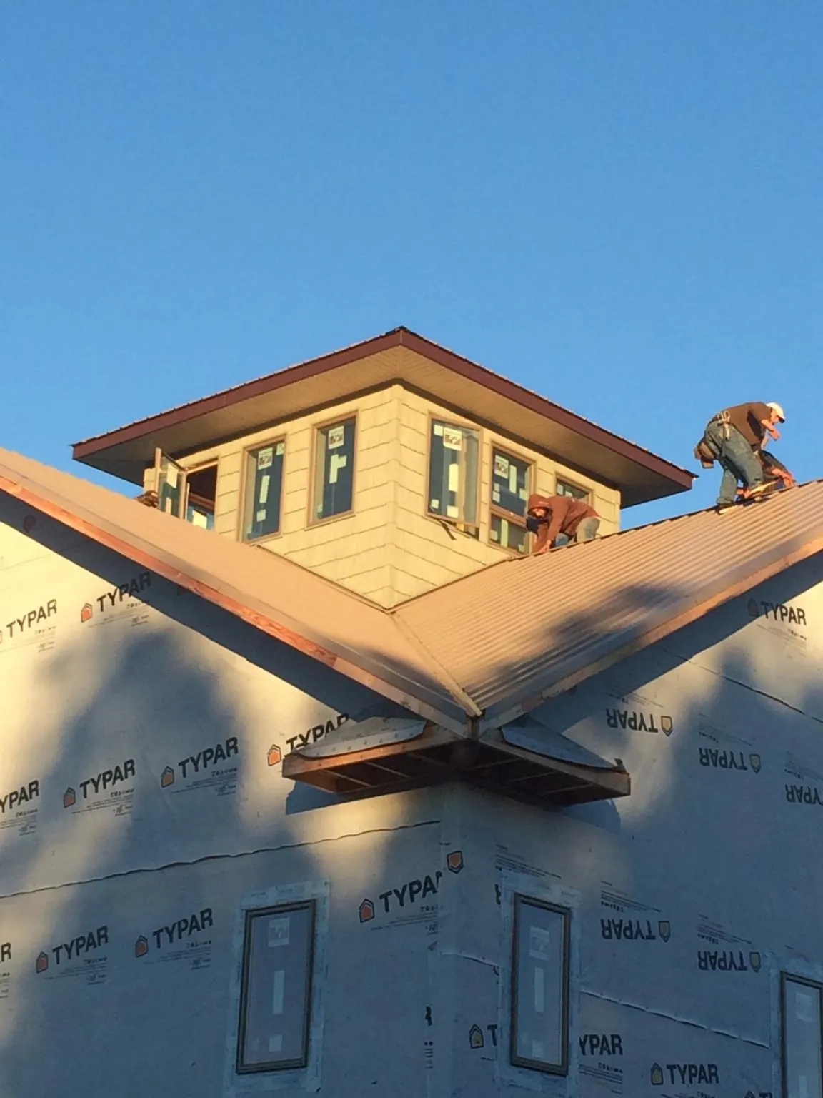 Roofers working around a rooftop cupola on a new metal roof at sunset — Roof Waterproofing in Valencia by Roofing Brothers